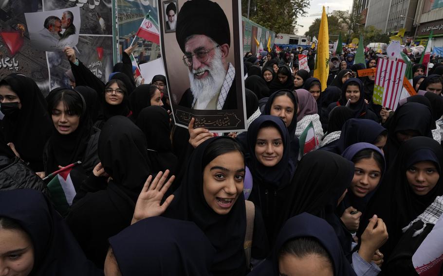 Students wearing black head scarves carry a picture of the Iranian supreme leader.