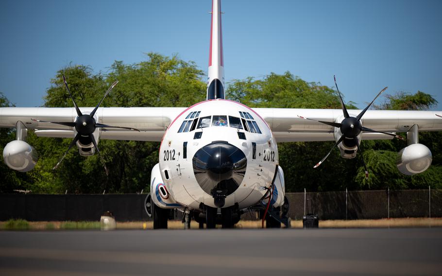 A military cargo plane, seen from the front, is parked on a tarmac.