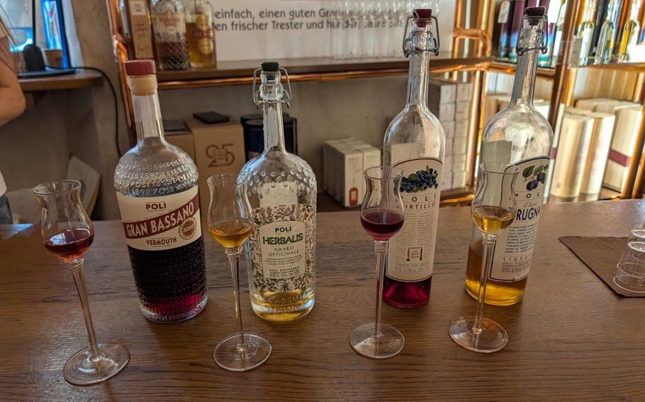 Bottles of grappa alcohol stand on a table at a distillery.