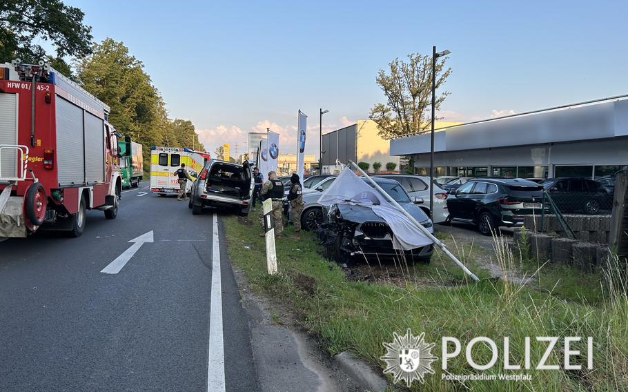 Emergency responders, including local police, firefighters and American military police, attend to the aftermath of a major accident on Kaiserstrasse, June 27, 2024. A 21-year-old American driver veered off the road and collided with several parked cars at a dealership, causing extensive damage estimated in the hundreds of thousands of euros, police said.