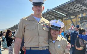 Two Marines in dress uniforms pose in a side-by-side embrace.