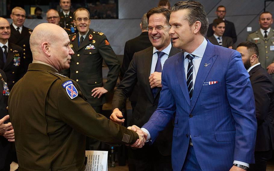 NATO’s supreme allied commander for Europe on the left, shaking hands with Defense Secretary Pete Hegseth who is in a blue suit on the right.