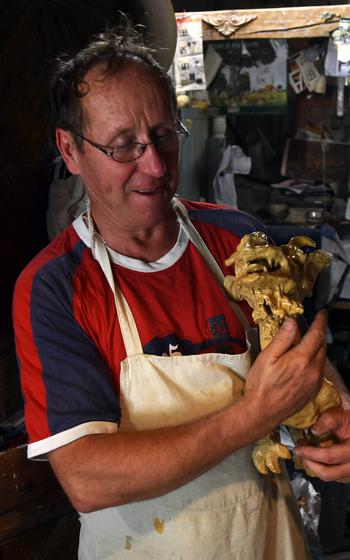 Potter Pascal Stecher holds one of his prized creations, a dragon he created in his tiny workshop in Betschdorf, France. Stecher often incorporates the themes of fantasy and sorcery into his work.