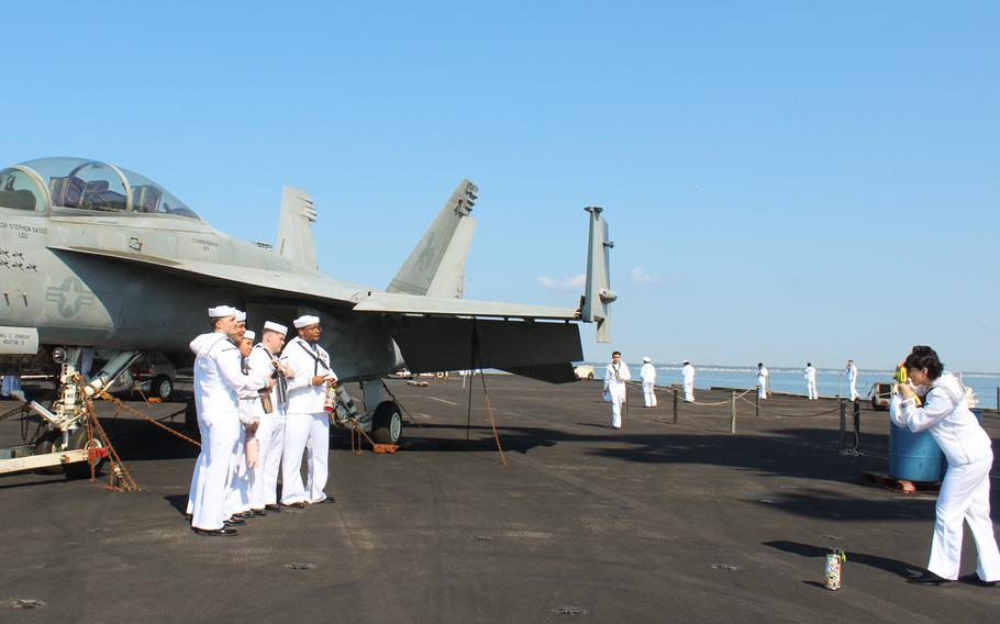 Sailors pose in front of an F-18 fighter jet onboard the USS Dwight D. Eisenhower on July 14, 2024, as the aircraft carrier returned to its homeport of Norfolk Naval Station in Virginia.