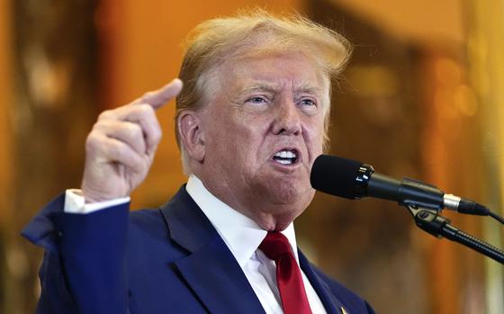 Donald Trump raises his arm and makes a pointing gesture while making a point during a news conference.