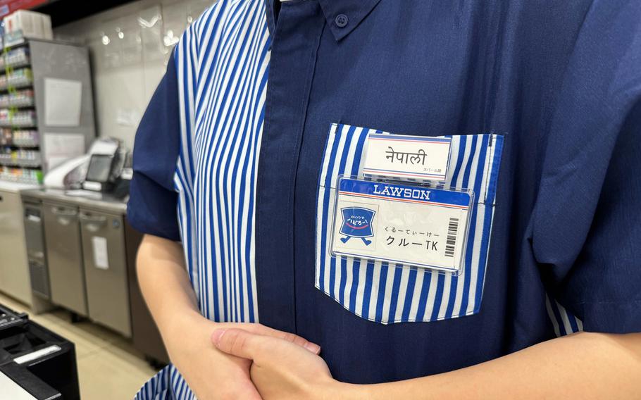 An employee at a supermarket in Lawson shows an ID card that identifies him as a Nepali language speaker. 