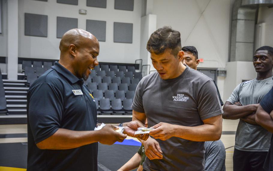 Kenneth Lee, right, of  Prep Wrestling Academy, receives a challenge coin from Dion Jordan, chief of sports, fitness and aquatics, during a wrestling seminar at Carey Fitness Center at Camp Casey, South Korea, June 18, 2024.