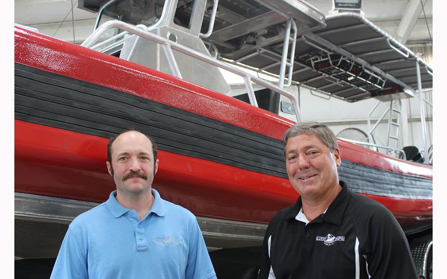 Steven Clarke, CEO of Silver Ships, left, and Shawn Lobree, the company’;s federal contracts manager, stand in front of a safety vessel designed for use in U.S. Marine Corps training exercises.