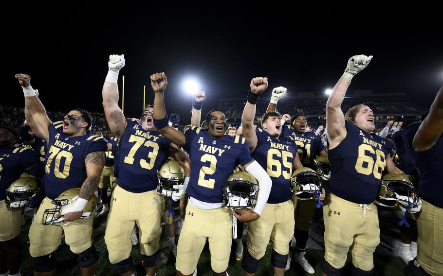 Navy players raise their arms in celebration after a victory against Charlotte.