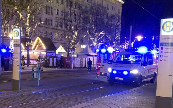 An emergency vehicle is seen at night on a street illuminated with Christmas decorations.