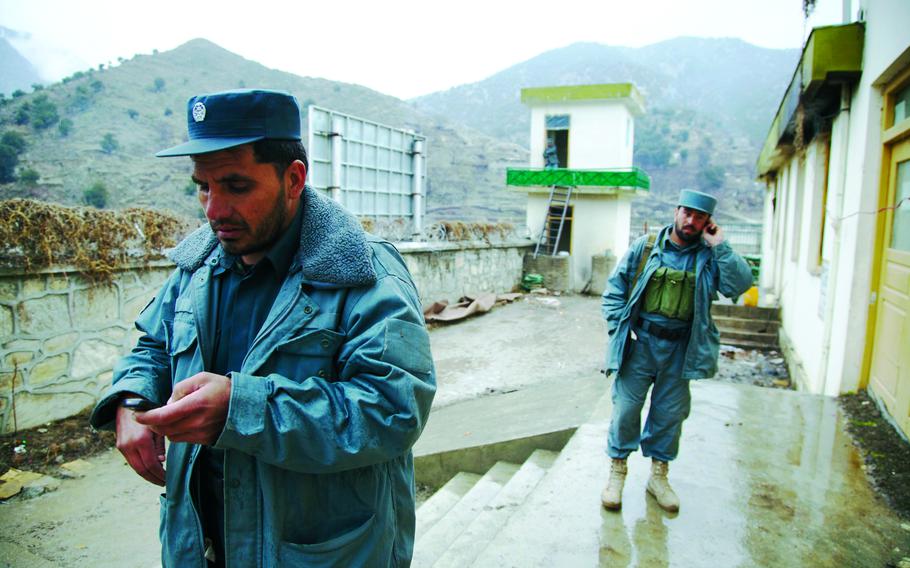 Afghan police talk on their phones and check messages 