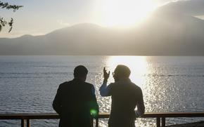 Marco Rubio and Nayib Bukele look out over the lake, with mountains and a low sun in the background.