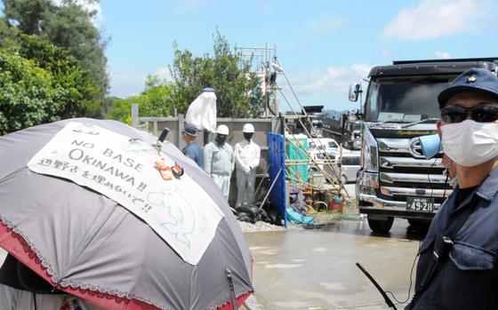 Anti-base protesters walk slowly to obstruct construction vehicles at the exit of Awa Port in Nago city, Okinawa, Thursday, Aug. 22, 2024.