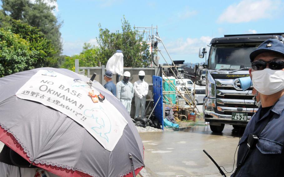 Anti-base protesters walk slowly to obstruct construction vehicles at the exit of Awa port in Nago city, Okinawa, Thursday, Aug. 22, 2024.