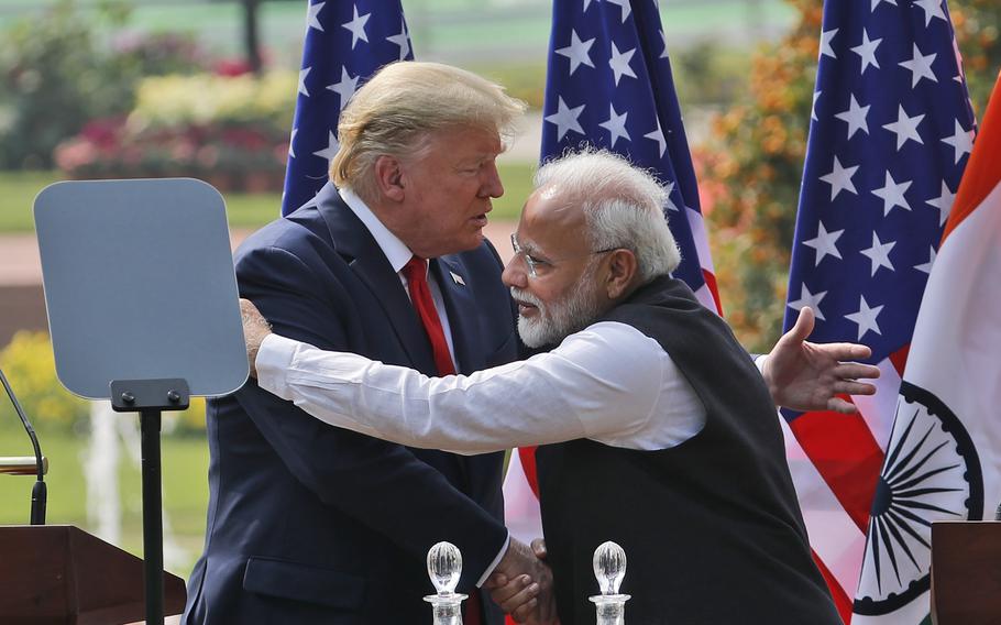 President Trump and Prime Minister Modi move to embrace one another while also shaking hands.