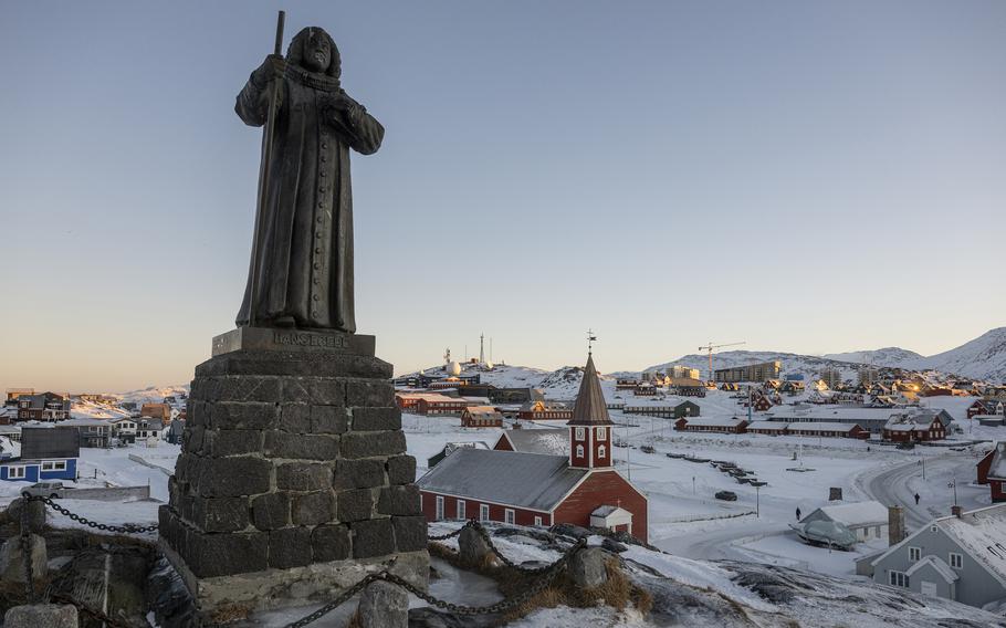 The statue of Hans Egede stands in a snow-covered village in Greenland.