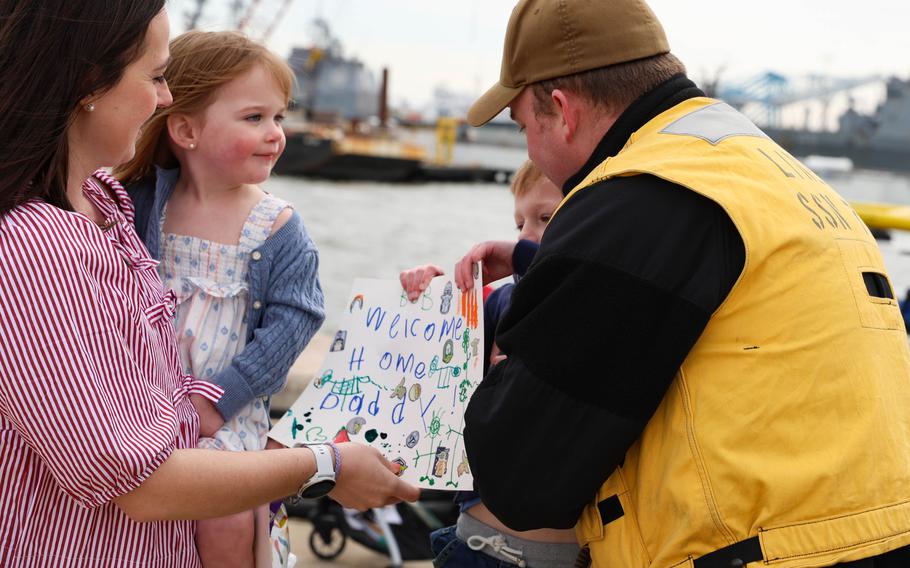 A sailor embraces his wife and daughter