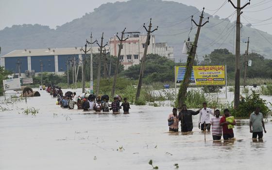 People, many carrying their belongings, wade through a flooded road after heavy rains in Vijayawada, India, Monday, Sept. 2, 2024. (AP Photo)