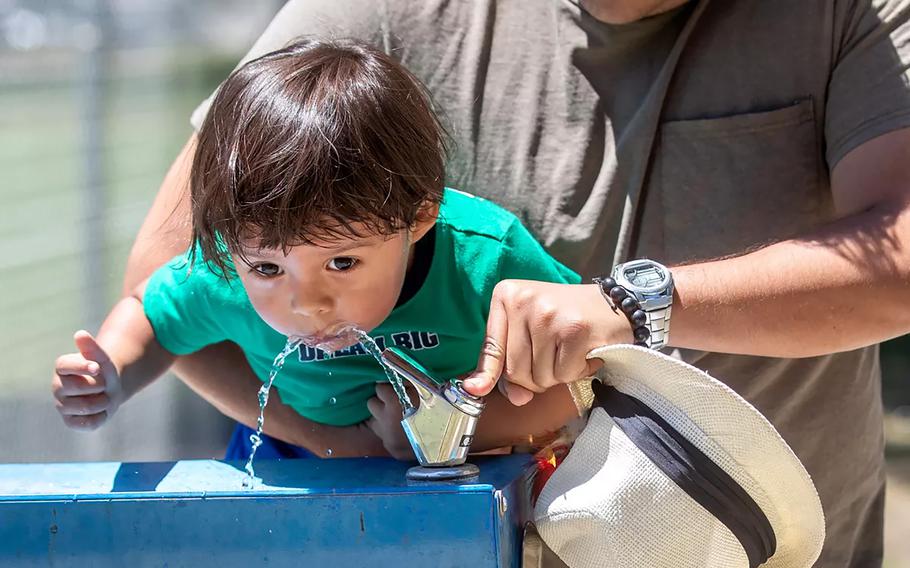 Abe Perez lifts his 2-year-old son, Mavy, for a drink of water from a fountain at Lanark Park in the Canoga Park neighborhood of Los Angeles, on a hot summer afternoon. 