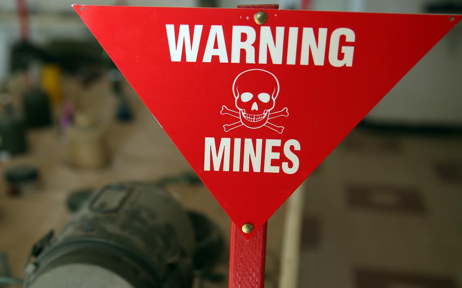 A red sign with a skull and crossbones reads, “Warning Mines.”