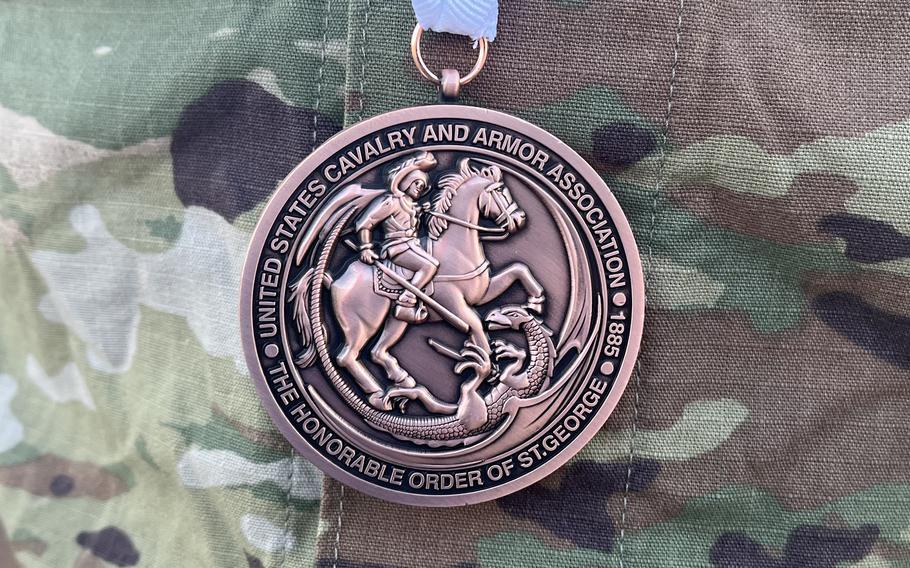 A medal with a blue ribbon adorns a U.S. Army uniform. 