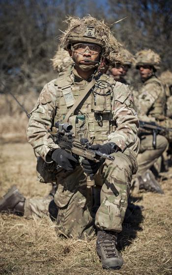 A Royal Military Academy Sandhurst cadet kneels while holding a gun preparing for a live-fire platoon attack.