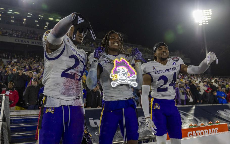 Football players hold a light up pirate sign to celebrate their win.