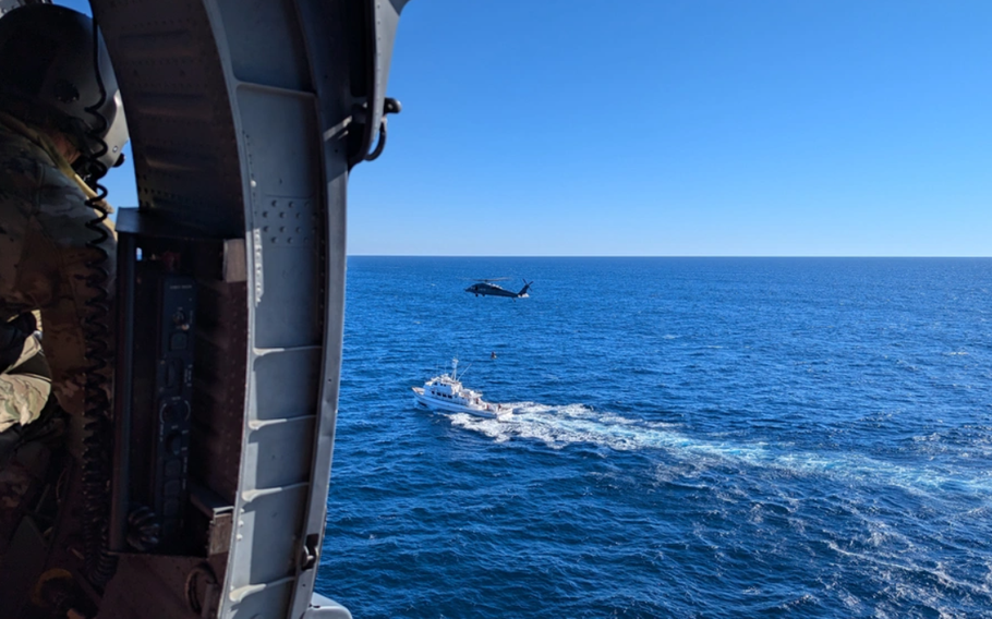 U.S. Air Force HH-60G Pave Hawk rescue helicopter hovers over a fishing vessel.