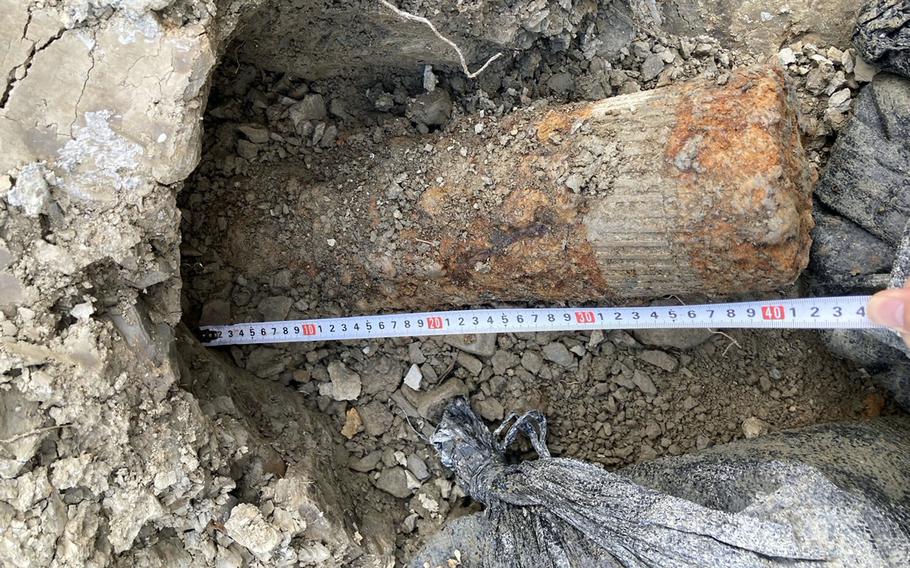  A U.S.-made shell believed to be from World War II is shown next to a tape measure.