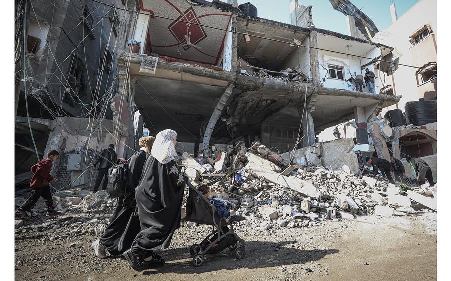 People walk past rubble structures in Gaza on Feb. 24, 2024.