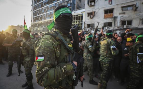 Fighters from the Qassam Brigades, the military wing of Hamas, control the crowd as Red Cross vehicles manoeuvre to collect Israeli hostages to be released under a ceasefire agreement between Israel and Hamas, in Gaza City, Sunday, Jan. 19, 2025. (AP Photo/Abed Hajjar)