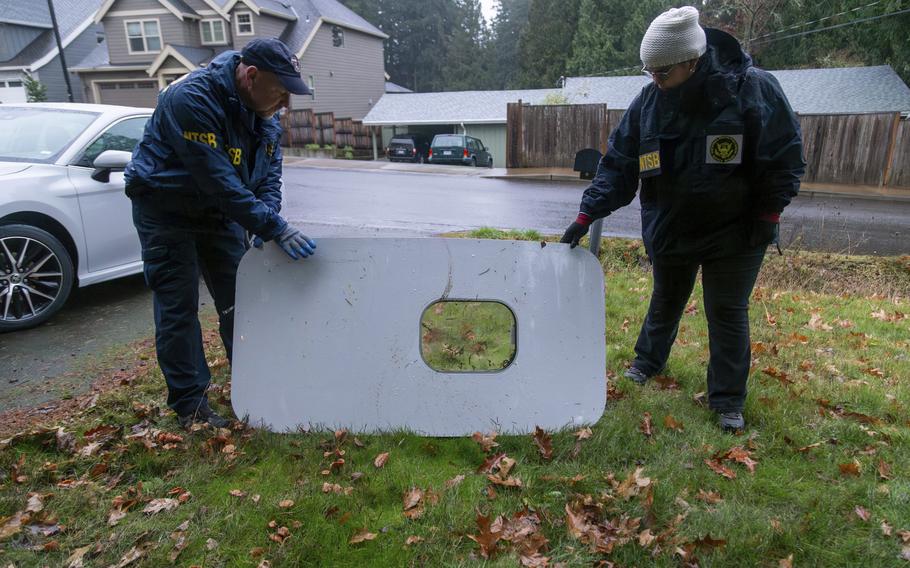 Two investigators prop up an airplane door component on someone’s lawn.