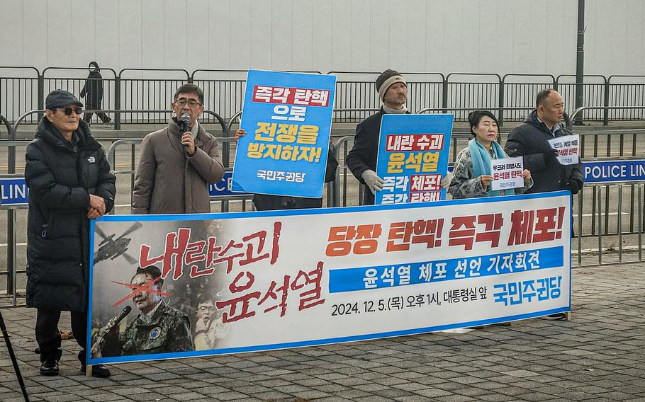 Protesters hold signs and stand behind a banner outside the office of of South Korean President Yoon Suk Yeo.