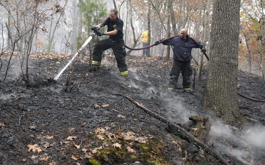 Firefighters work to put out a brush fire