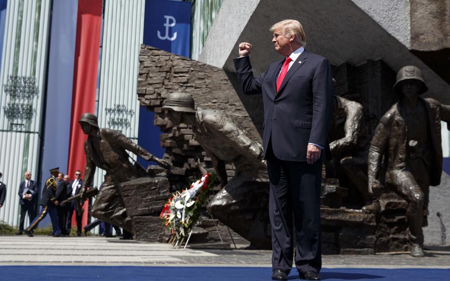 President Donald Trump clenches his right fist as he stands in front of the Warsaw Uprising Monument on Krasinski Square.