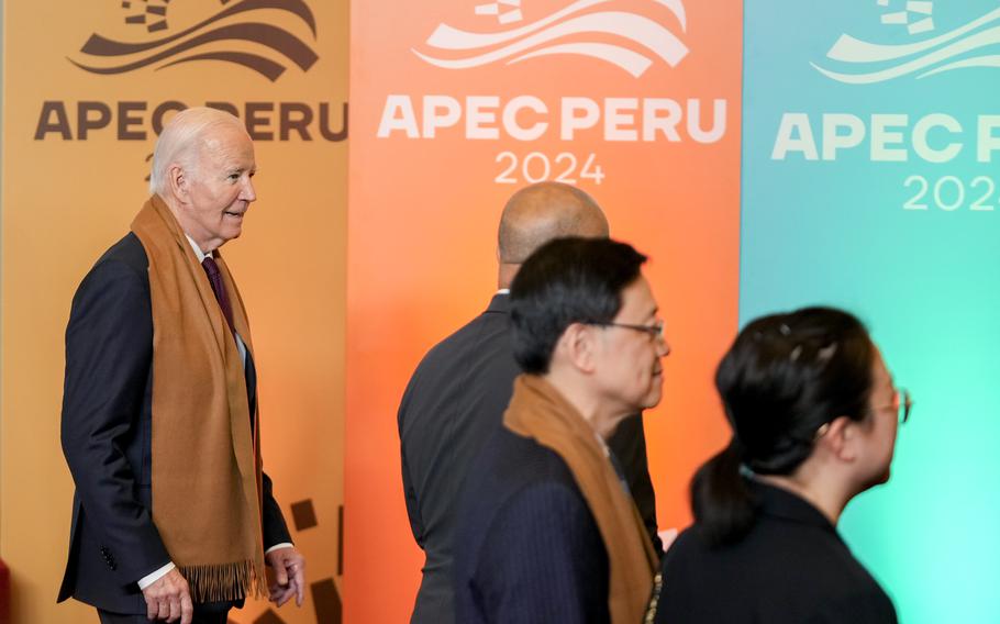 President Biden walking with other foreign leaders against posters for the APEC summit in Lima, Peru, Nov. 16, 2024. 