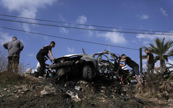 Palestinians gather around a car destroyed in a drone strike Zeita village, north of the West Bank city of Tulkarem, Saturday, Aug. 3, 2024. The Israeli military says it struck five suspected terrorists in a vehicle on their way to carry out an attack. 