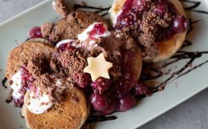 Buttermilk, banana and marzipan pancakes topped with creamy almond yogurt and chocolate biscuit crunch at Ennie's in Homburg, Germany. A scattering of tart Speculoos cherries spread provides a sharp, spiced contrast, evoking warm flavors of Christmas.