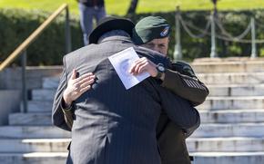 Two men embrace at a wreath-laying ceremony at Arlington National Cemetery, Va., on Oct. 17, 2024.