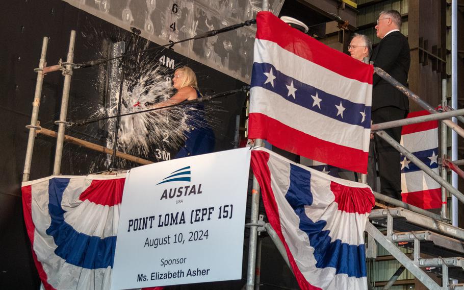 Ship sponsor Elizabeth Asher smashes the champagne bottle during the christening ceremony for the future USNS Point Loma on Saturday in Mobile, Ala.