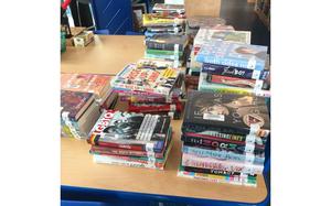 Books that have been temporarily removed recently for a compliance review are stacked up on a table in the library at Ramstein High School in Germany. Many of the books that have been singled out touch on LGBTQ+ topics. The review was prompted by recent executive orders.
