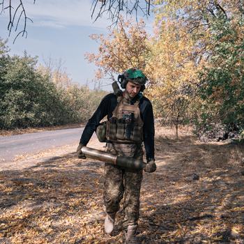 A Ukraine soldier with an artillery shell.