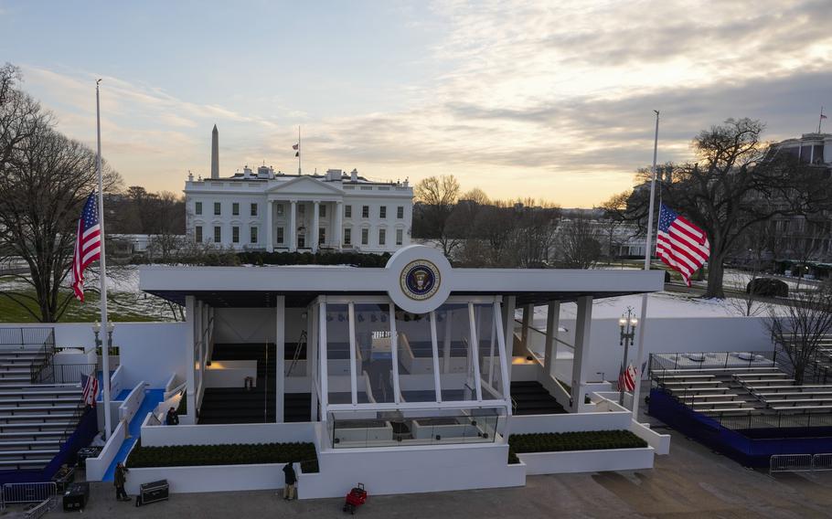 A protected stand is set up outside of the White House with snow visible in the lawn between the structures.