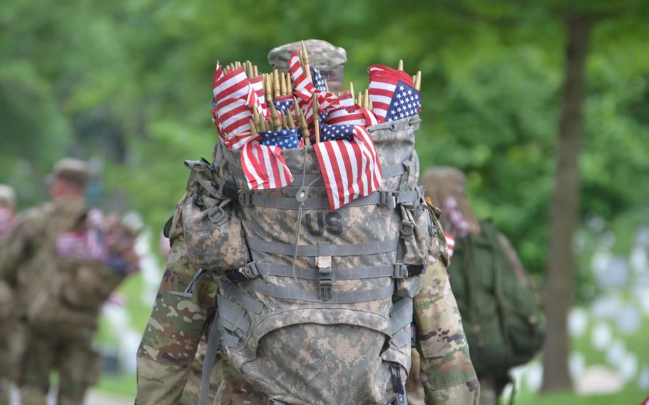 A soldier from the 3rd Infantry Regiment, also known as The Old Guard, prepares to place flags at gravesites at Arlington National Cemetery on Thursday, May 23, 2024, to honor fallen service members for Memorial Day. 