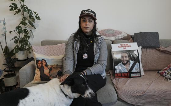 Released hostage Ilana Gritzewsky poses for a portrait in her apartment in Kiryat Gat, Israel, on Sunday, Dec. 15, 2024, near photos of her boyfriend, Matan Zangauker, who is being held hostage by Hamas in the Gaza Strip. (AP Photo/Tsafrir Abayov)
 