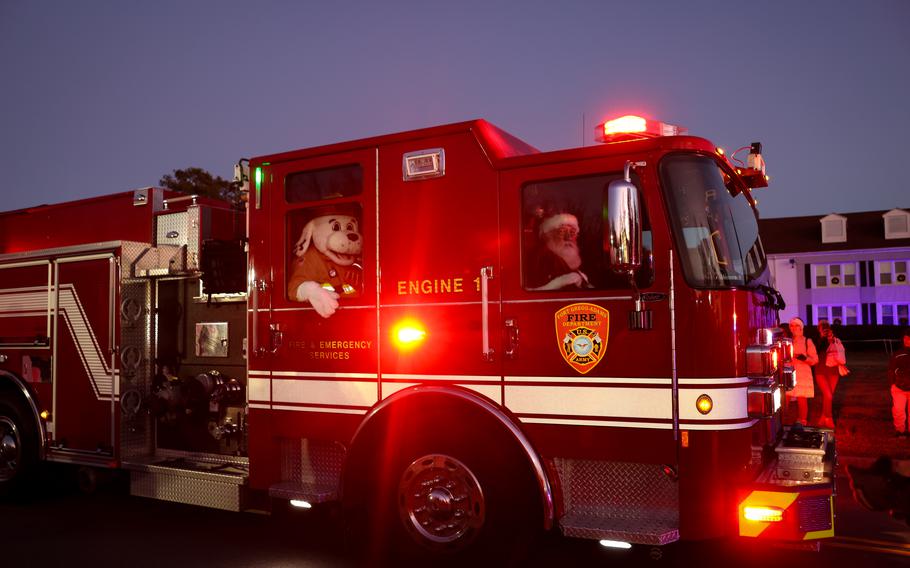 Santa rides in the front seat of a firetruck.