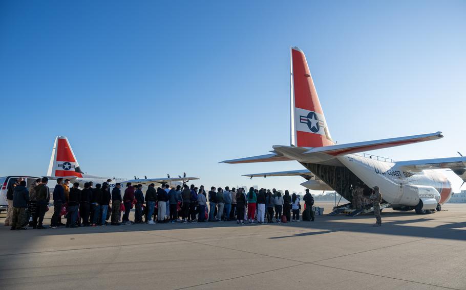 People on a tarmac boarding an aircraft.