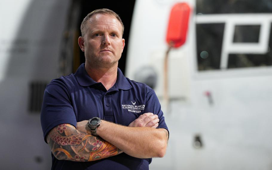 Former Air Force Osprey pilot Brian Luce stands with arms crossed in front of an aircraft on display at the Wright Patterson AFB Air Force Museum.