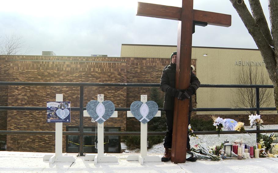 Three crosses and a man holding a cross taller than him.