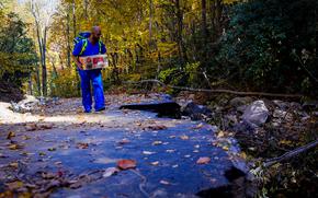 Corey Anderson, an intermediate care technician with the Asheville, N.C., Veterans Affairs Department medical center, carries medical supplies on a mountain road near Asheville, N.C., which was devastated by flooding and landslides from Hurricane Helen, which hit Sept. 27. (Photo by Kathie Ramos/Asheville VA)